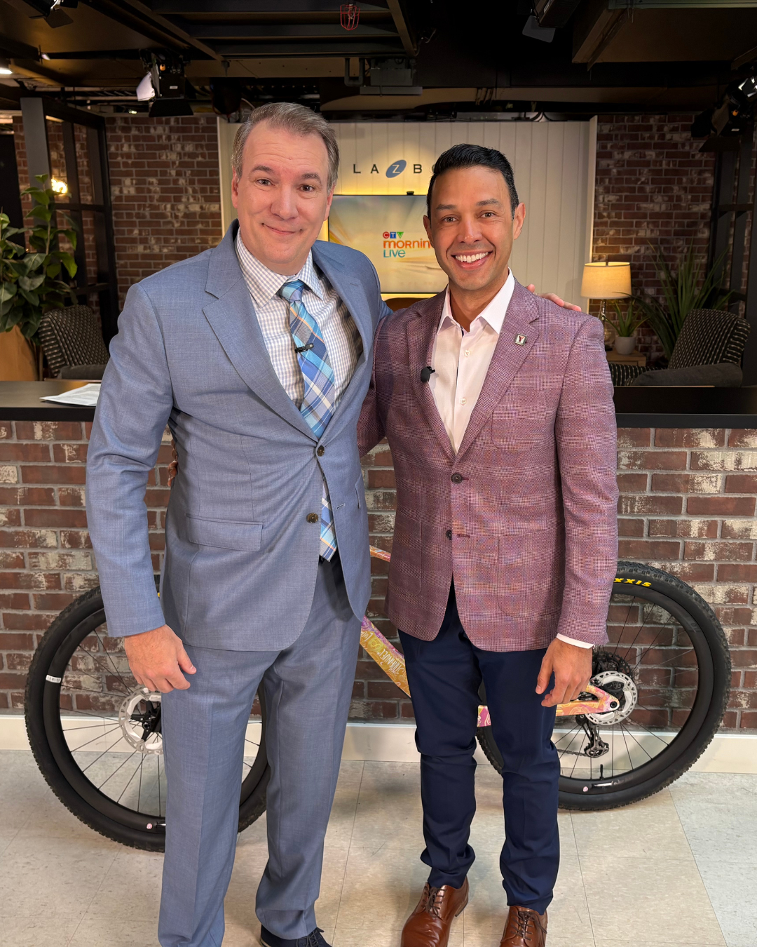 Jeff Hopper and Morgan Bello standing in the CTV Morning Live Lounge in front of Morgan's bike