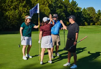 Four golfers high fiving on a golf course