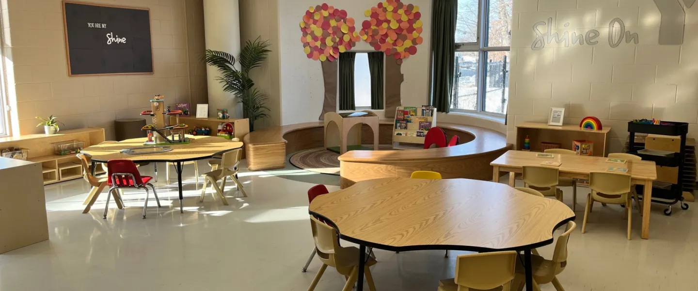 Churchill Child Care Centre interior. There are small chairs, tables, toys, and decorations.