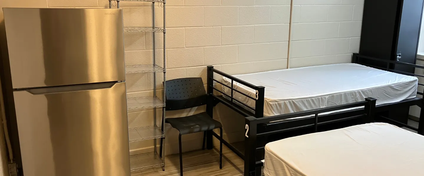 A bedroom with two twin beds and a refrigerator