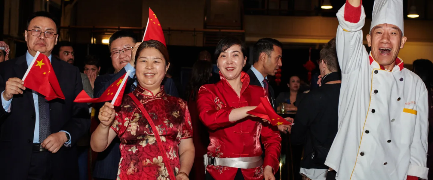 A group photo of folks from the Chinese Embassy waving small Chinese flags