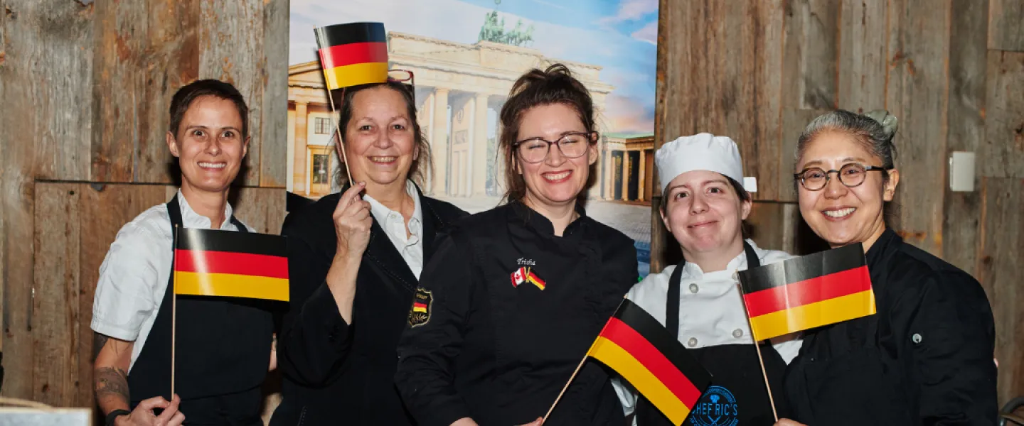 A group photo of chefs from the German Embassy holding up small German flags
