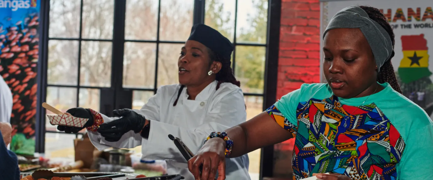 Two people serving food at the Ghana booth