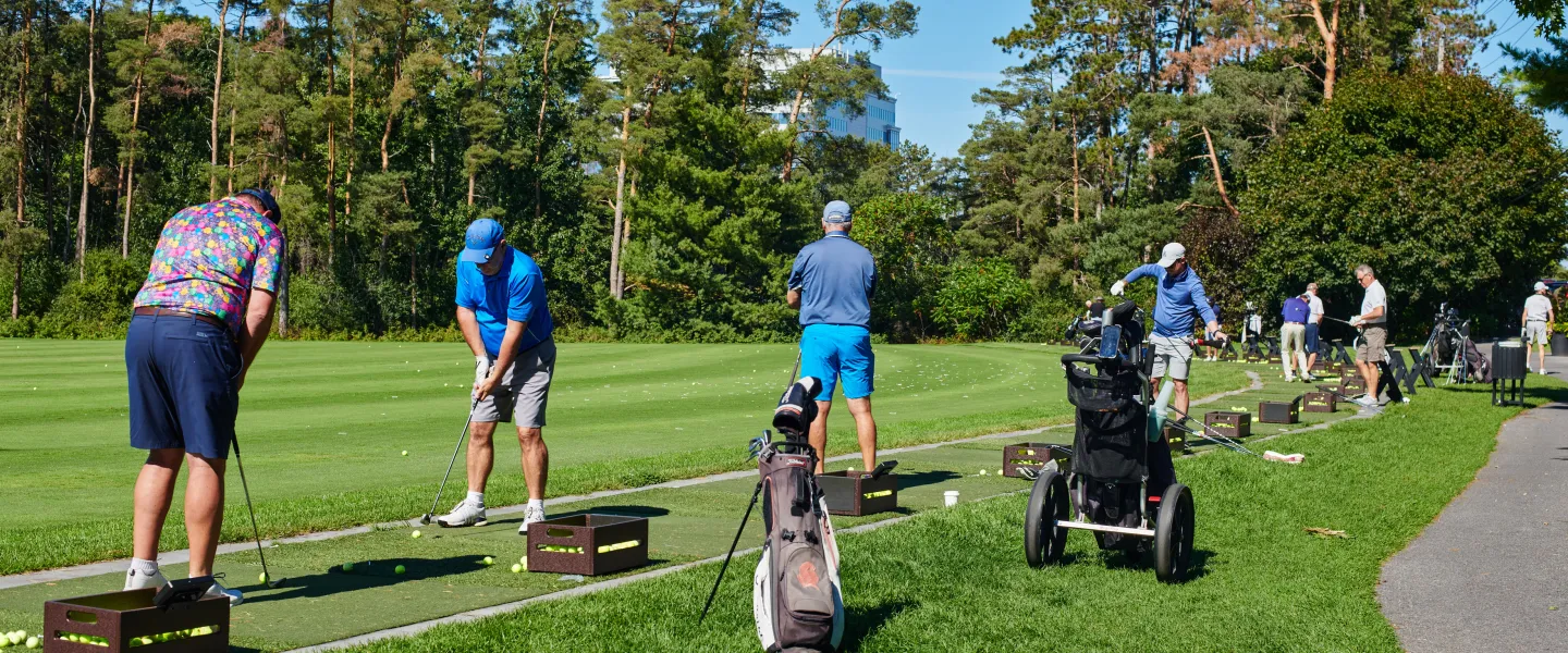 A group of golfers lined up at tees on a golf course