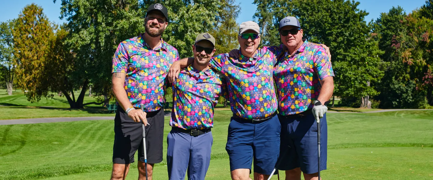 Four golfers standing together, wearing matching multicoloured shirts