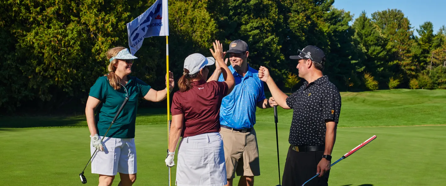 Four golfers high fiving on a golf course