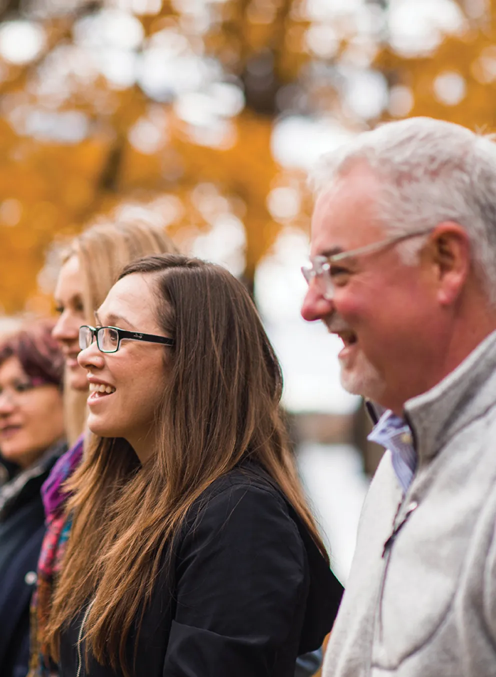 A group of adults standing outside in an autumn setting.