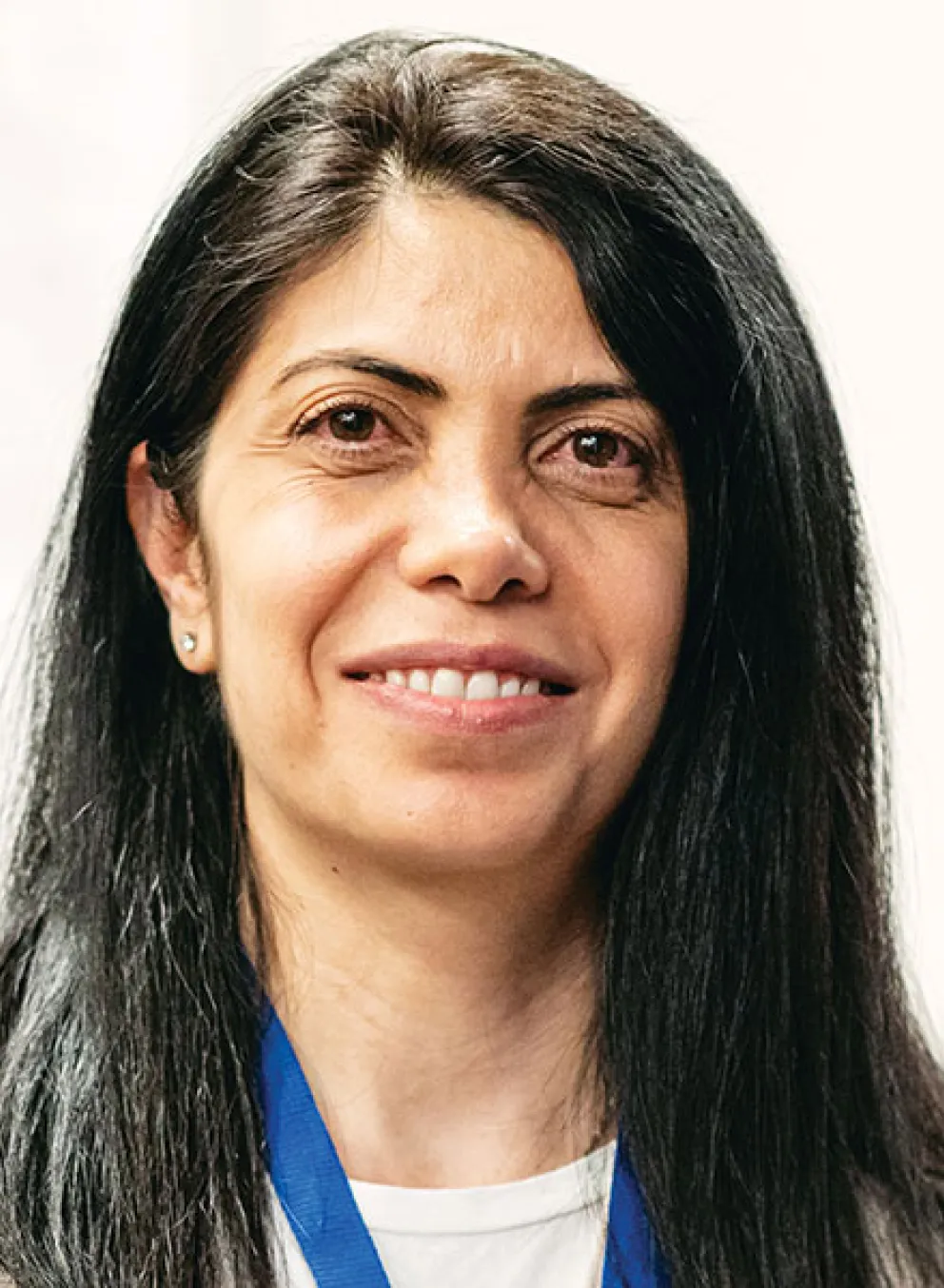 A woman with long black hair, smiling softly while facing the viewer.