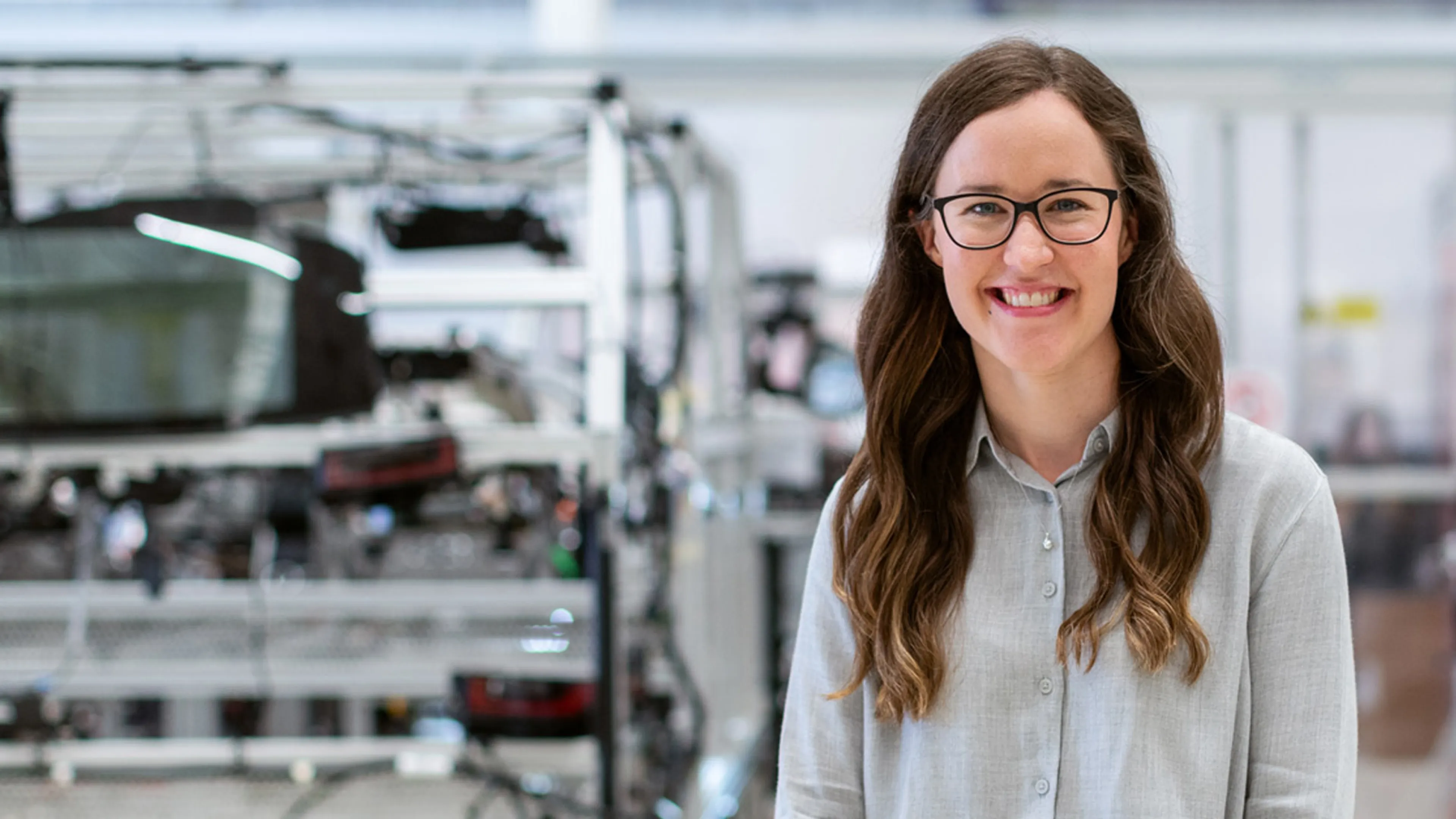 A smiling woman stands in a factory.