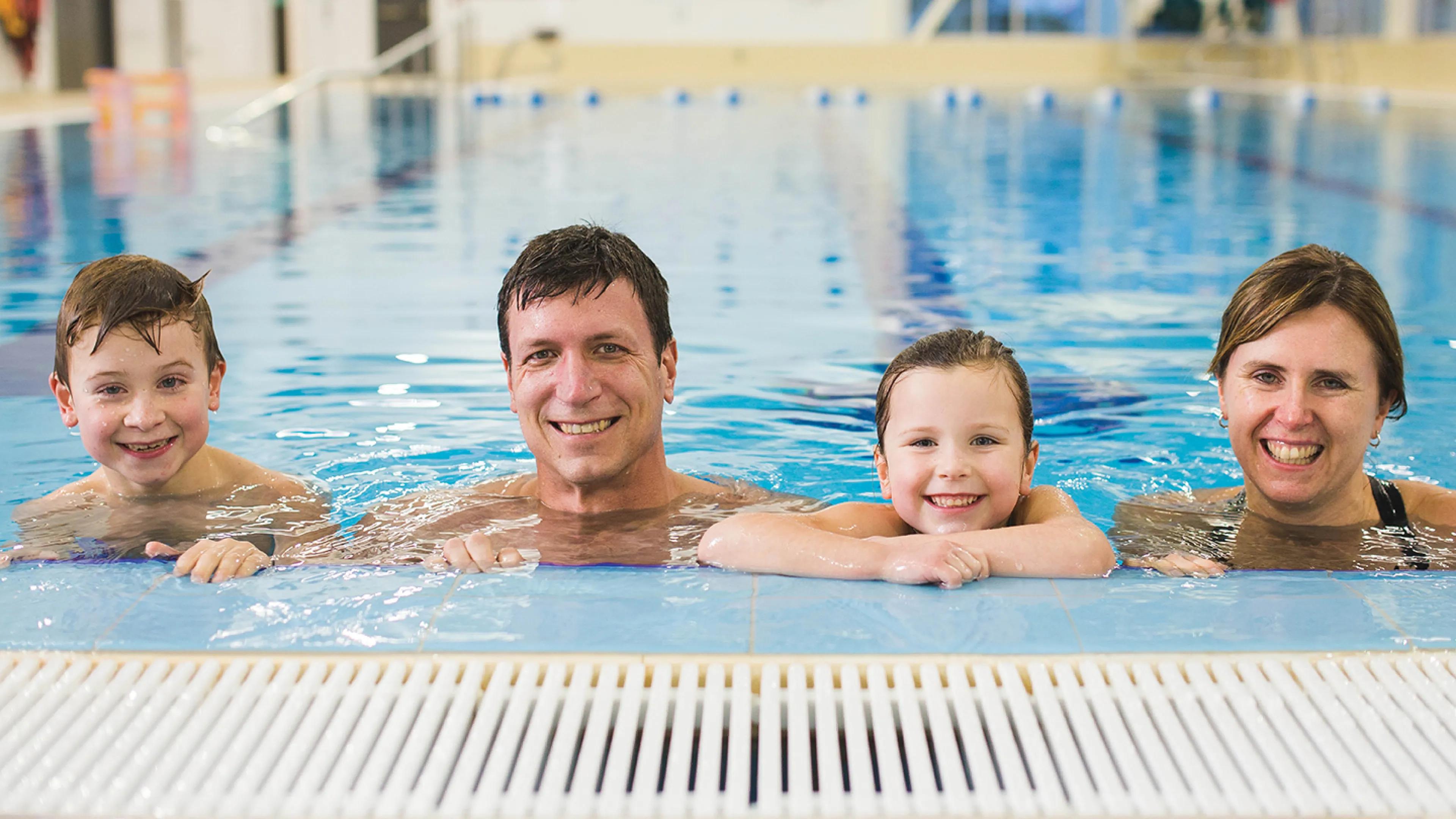 A family of four at the edge of a swimming pool
