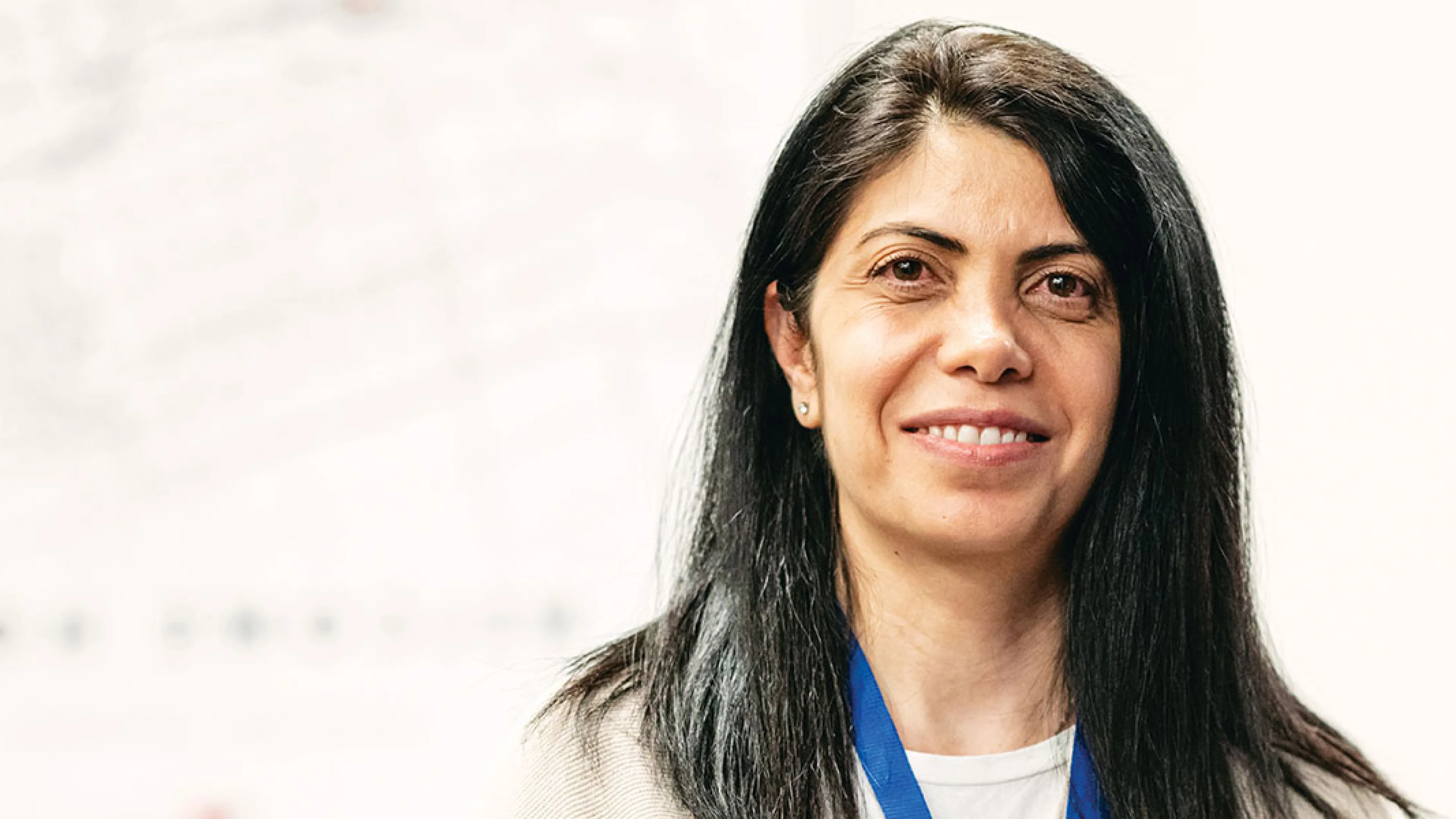A woman with long black hair, smiling softly while facing the viewer.
