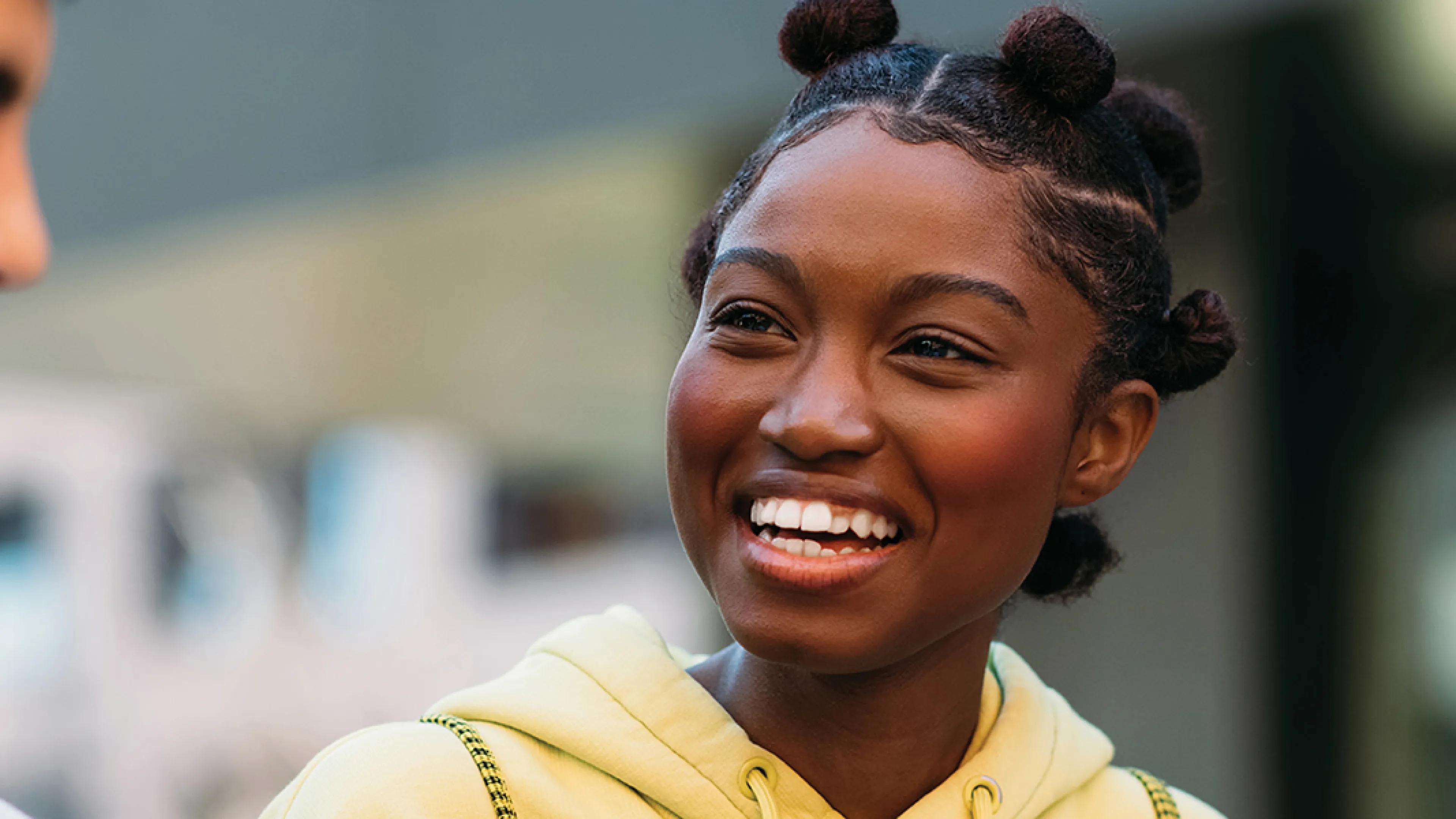 A young woman smiles while engaging in conversation.