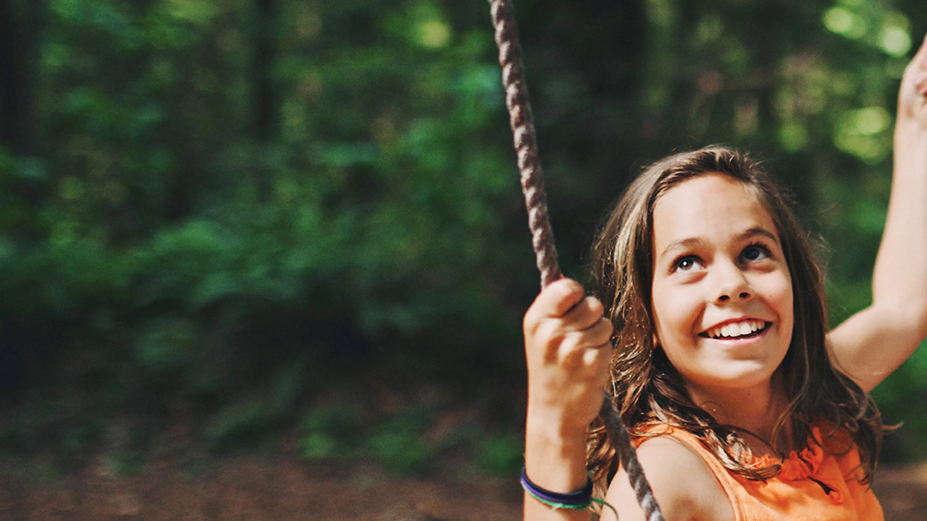 A young girl beams with happiness as she swings back and forth on a swing.