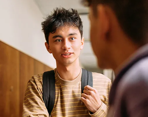 A young man engages in conversation with another man, both appearing attentive and interested in the discussion.